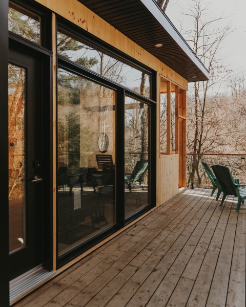 Wooden cabin with glass doors and forest-view deck.